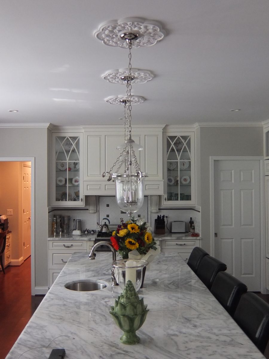 Clean, traditional renovated kitchen with hanging glass overhead lights and marble counter