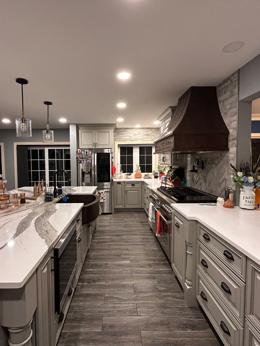 Renovated kitchen of private residence includes marble counter island and black metallic farmhouse sink