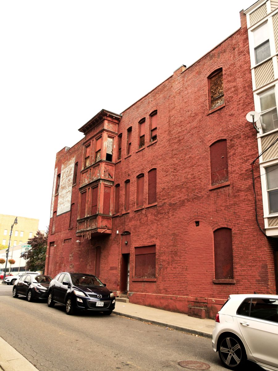 Abandoned red brick building with boarded windows