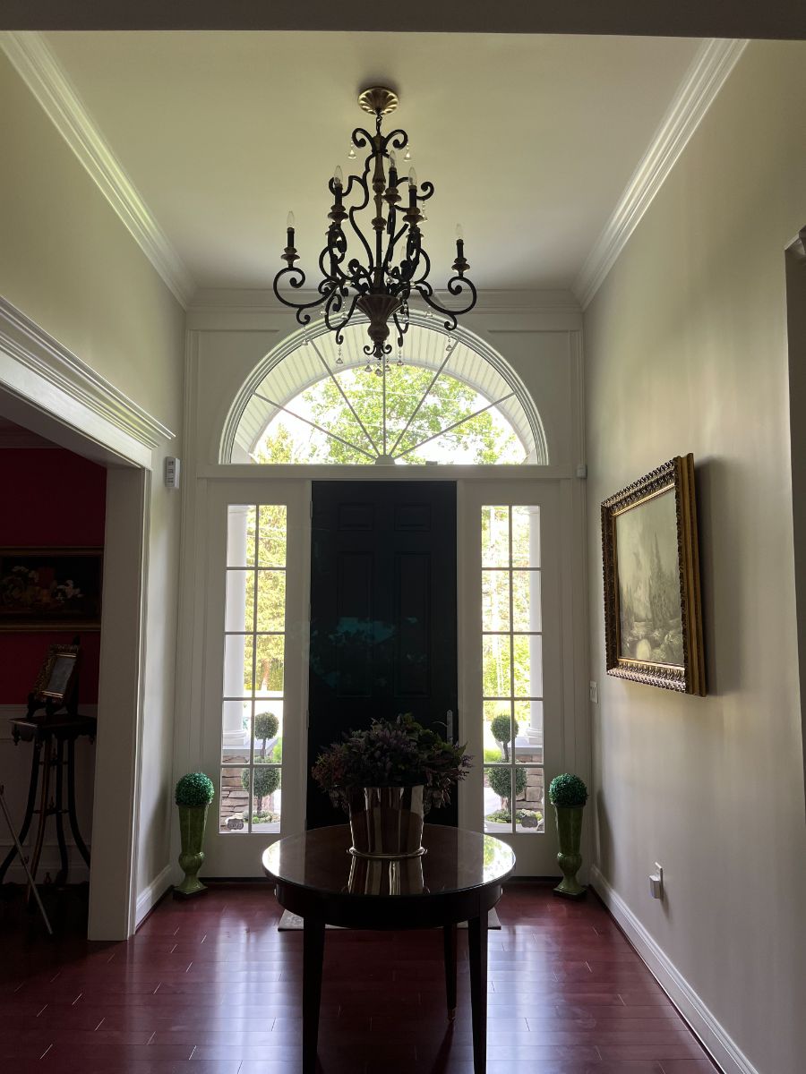 Main foyer with antique chandelier and mahogany floors in renovated private residence